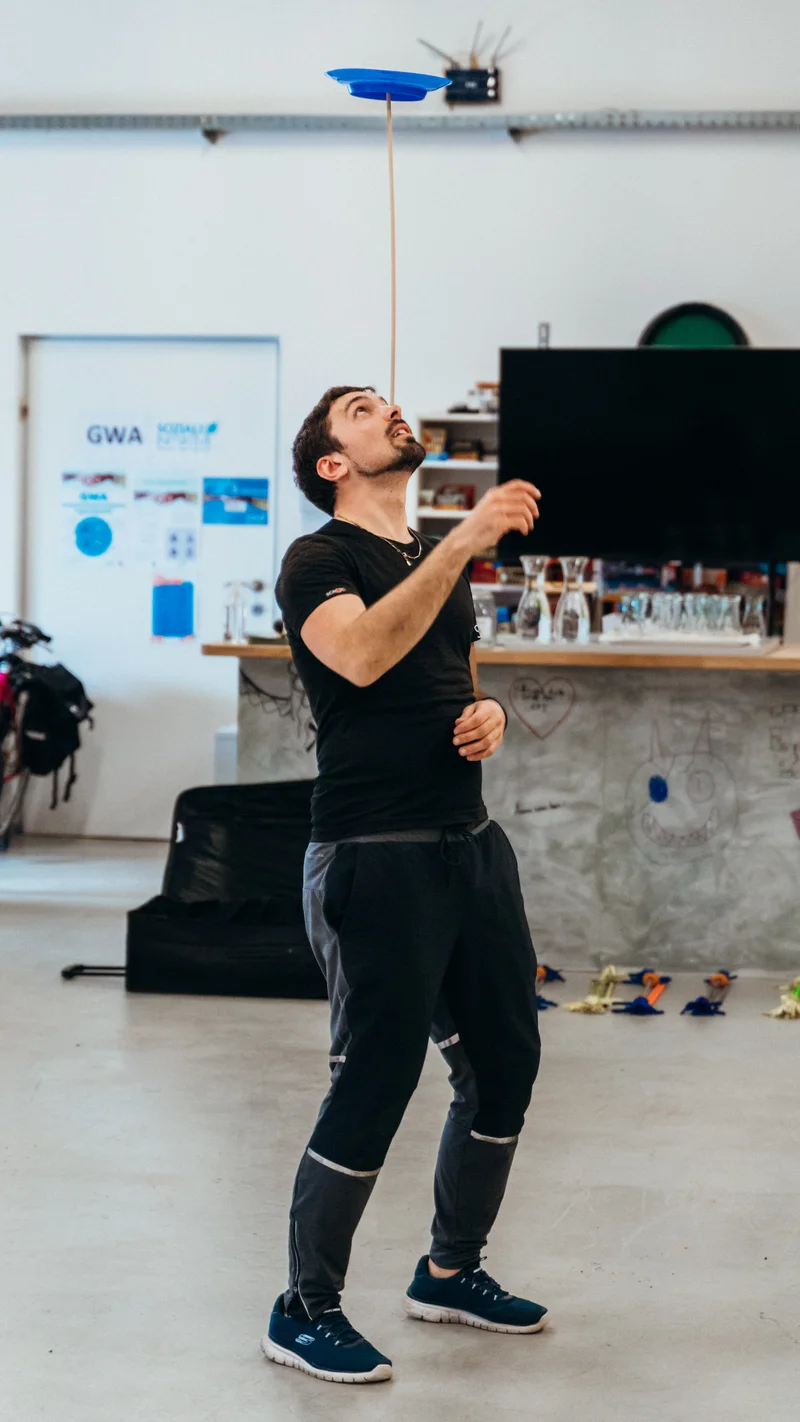 RawmanPictures - Sebastian Schiefermayr | Jonglierworkshop Marchtrenk | Kreative Studiofotografie: Mann balanciert Teller. Geschicklichkeit und Konzentration im Fokus.