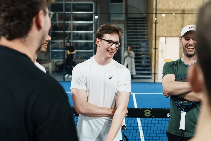 RawmanPictures - Sebastian Schiefermayr | Padelbase Videodreh | Lachende Tennisspieler im Gespräch auf dem Platz – Sportfotografie, Dynamik und Emotionen festgehalten.
