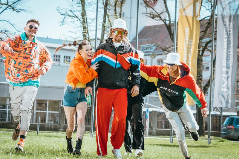 RawmanPictures - Sebastian Schiefermayr | Musikvideodreh "Flinz Asozial" | Gruppe fröhlicher Menschen in bunter Retro-Mode, Outdoor-Porträt, urbanes Leben, Streetstyle.