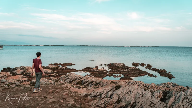 RawmanPictures - Sebastian Schiefermayr | Maturareise Kroatien | Mann genießt Küstenblick: Landschaftsfotografie am Meer bei Sonnenuntergang, Entspannung am Wasser.