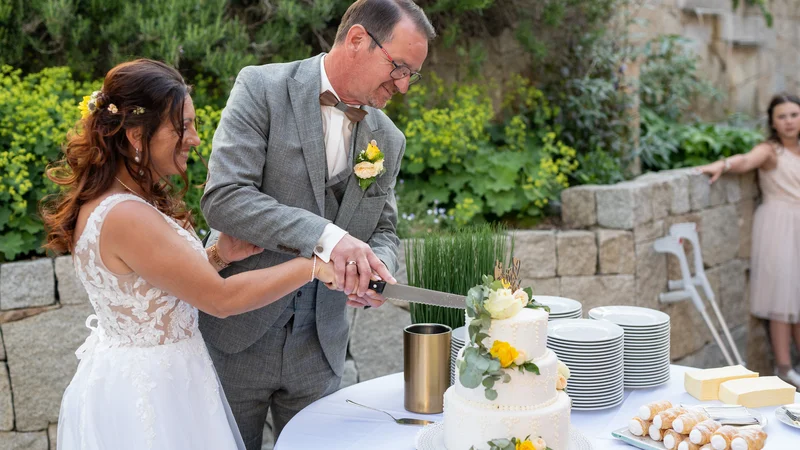RawmanPictures - Sebastian Schiefermayr | Hochzeit Traude & Gerhard | Hochzeitsfotografie: Paar schneidet Hochzeitstorte im Freien an, unvergessliche Momente festhalten.