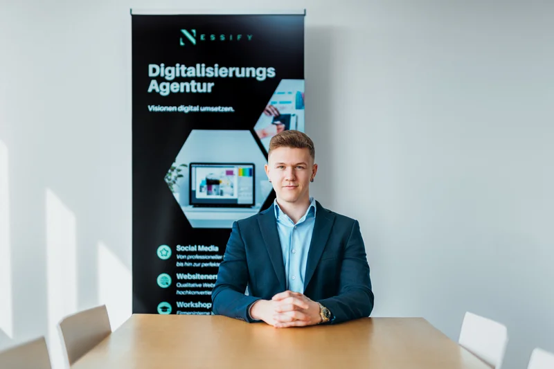 RawmanPictures - Sebastian Schiefermayr | Bussines-Shooting Nessify | Professioneller Agenturvertreter vor Werbebanner für digitale Dienstleistungen.