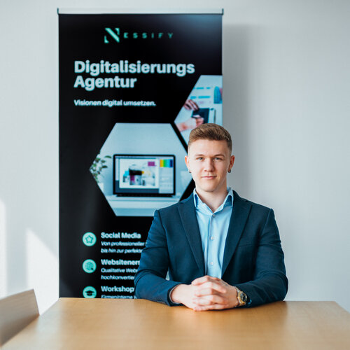 RawmanPictures - Sebastian Schiefermayr | Bussines-Shooting Nessify | Professioneller Agenturvertreter vor Werbebanner für digitale Dienstleistungen.