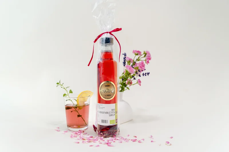 RawmanPictures - Sebastian Schiefermayr | Kräuter­manufaktur Sallmannsberg | Elegantes Produktfoto: Bio-Rosensirup, stilvoll arrangiert mit Blüten und Getränk. Ideal für Feinschmecker.