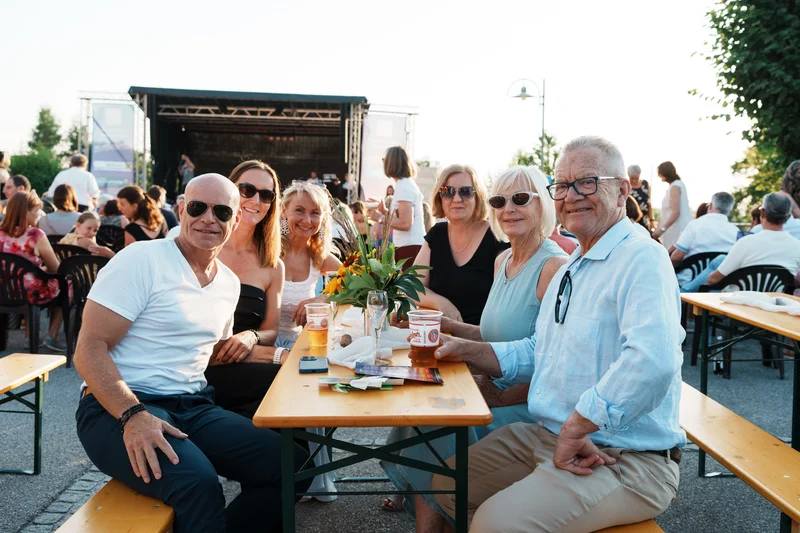 RawmanPictures - Sebastian Schiefermayr | Singkreis-Sundowner  | Gruppe von Menschen bei einem Sommerfest im Freien, entspannte Stimmung, soziale Begegnungen.
