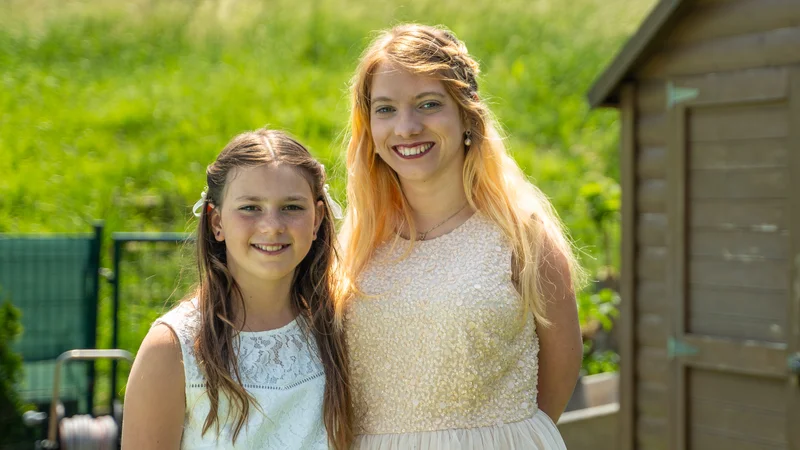 RawmanPictures - Sebastian Schiefermayr | Hochzeit Traude & Gerhard | Zwei lächelnde Mädchen im Garten, festliche Kleidung, natürliche Beleuchtung, Sommerporträt.
