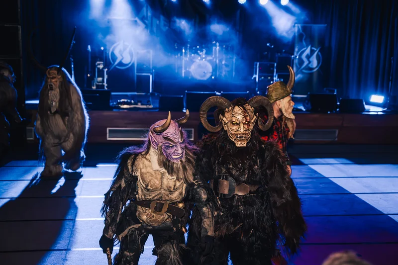RawmanPictures - Sebastian Schiefermayr | Krampusnacht | Kostümierte Figuren auf der Bühne bei einem Event, beleuchtet von bunten Lichtern.