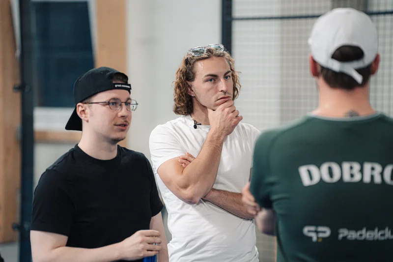 RawmanPictures - Sebastian Schiefermayr | Padelbase Videodreh | Gruppe bei Teambesprechung: Zusammenarbeit und Kommunikation im Fokus. Fotograf München.