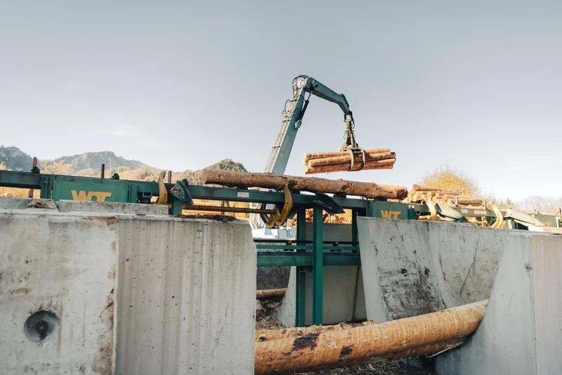 RawmanPictures - Sebastian Schiefermayr | Sägewerk Löberbauer | Holzverarbeitung: Industrieller Holzkran hebt Baumstämme für Sägewerk-Logistik und Waldwirtschaft.