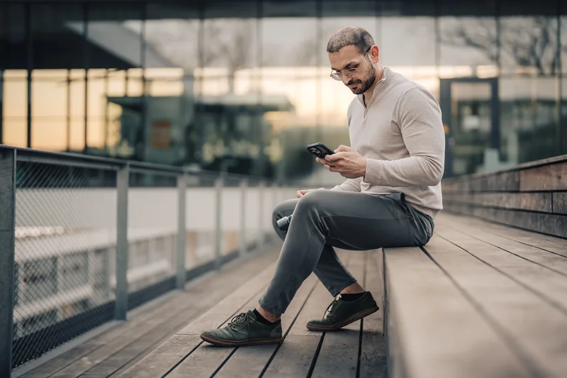 RawmanPictures - Sebastian Schiefermayr | Fotowalk Burhan | Urbaner Lifestyle: Mann mit Smartphone auf moderner Holzbank. Ideal für Businessportraits.