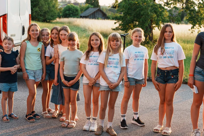 RawmanPictures - Sebastian Schiefermayr | Singkreis-Sundowner  | Gruppe von Kindern im Sommerlicht, gemeinschaftliches Outdoor-Erlebnis, Naturhintergrund.