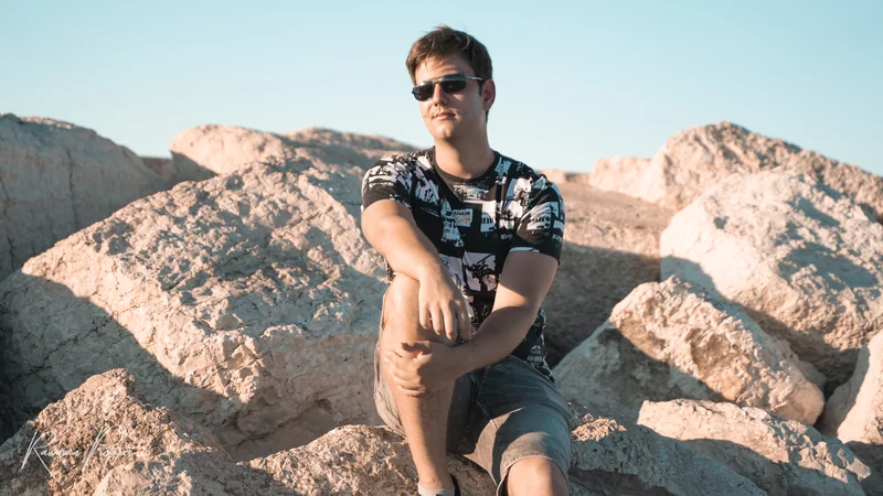 RawmanPictures - Sebastian Schiefermayr | Chioggia 2022 | Mann auf Felsen im Sonnenlicht, entspannte Pose, Outdoor-Porträtfotografie.