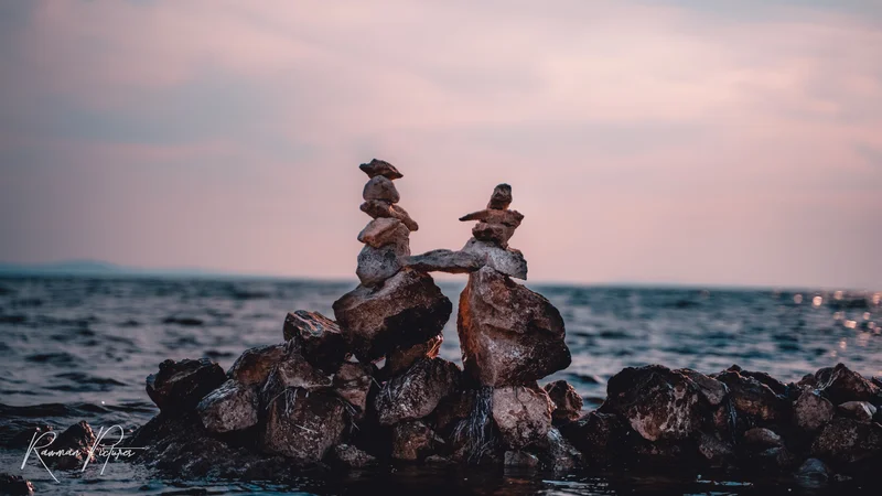 RawmanPictures - Sebastian Schiefermayr | Maturareise Kroatien | Steinbalance am Seeufer bei Sonnenuntergang, künstlerische Naturfotografie, Landschaftsaufnahme.