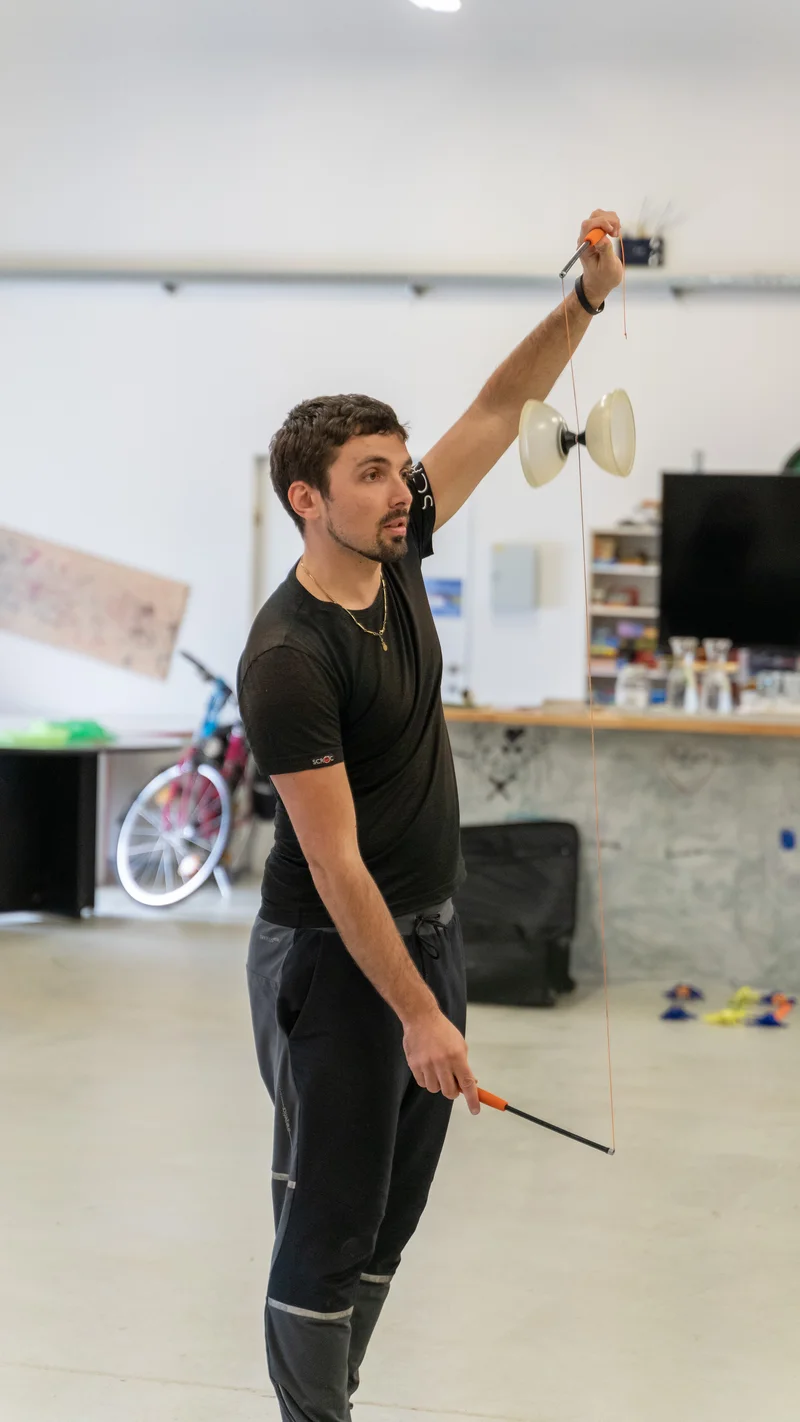 RawmanPictures - Sebastian Schiefermayr | Jonglierworkshop Marchtrenk | Mann jongliert mit Diabolo, konzentrierte Performance, kreative Fotografie, Freizeitaktivität.