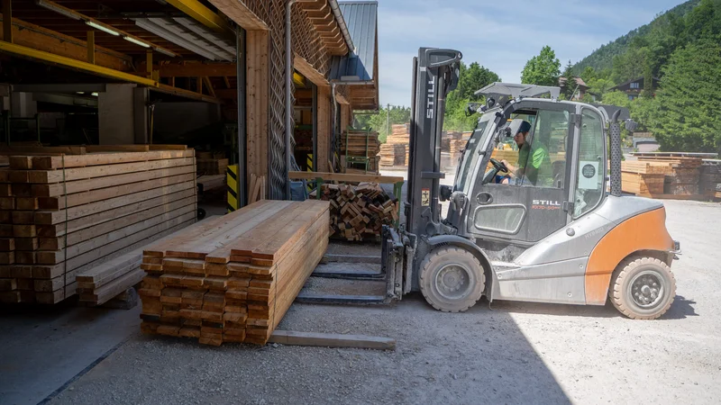 RawmanPictures - Sebastian Schiefermayr | Sägewerk Löberbauer | Gabelstapler transportiert Holzstapel in Sägewerk bei Tageslicht.
