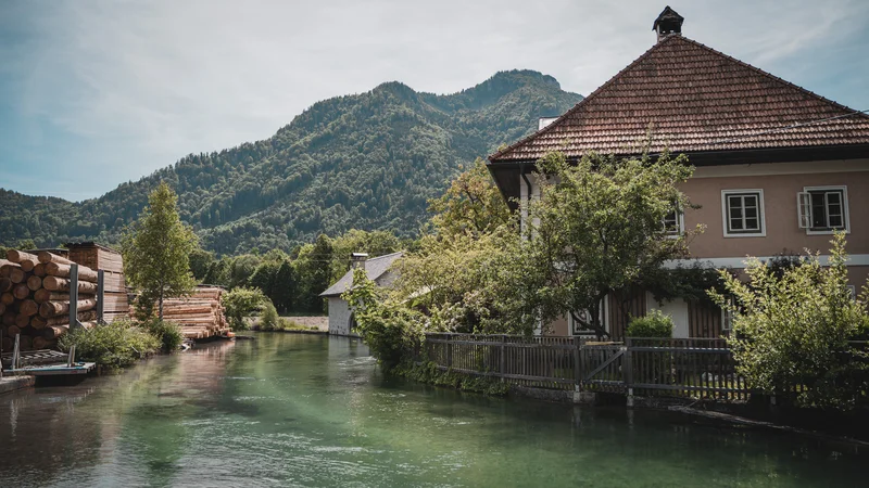 RawmanPictures - Sebastian Schiefermayr | Sägewerk Löberbauer | Landschaftsfotografie: Idyllisches Haus am Fluss mit Alpenpanorama im Hintergrund.