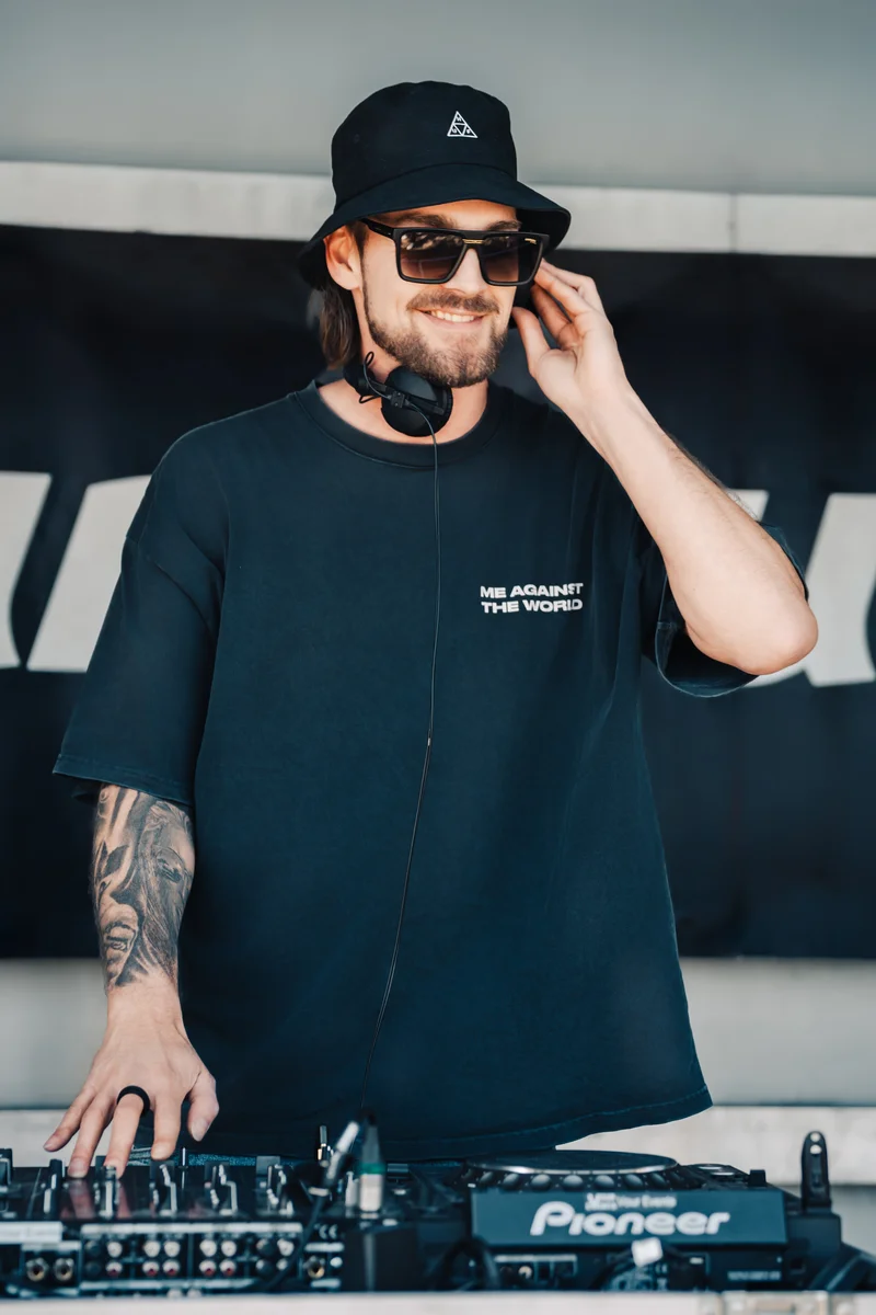 RawmanPictures - Sebastian Schiefermayr | Jay Escola b2b Nikkush | DJ-Porträt: Kreative Eventfotografie eines DJs am Mischpult mit stylischer Kleidung und Kopfhörern.