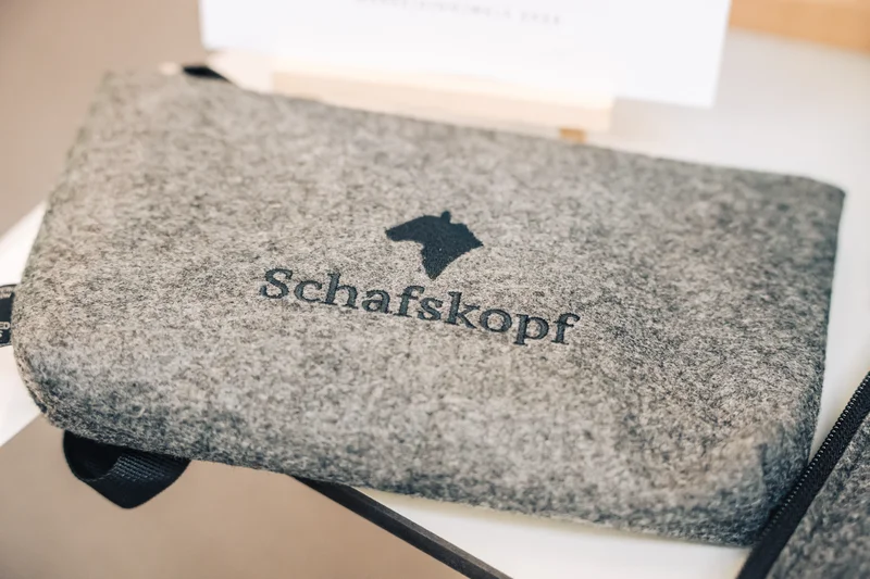 RawmanPictures - Sebastian Schiefermayr | Marke[ding] Wels | Graues Filzetui mit Schafskopf-Design in Nahaufnahme, handgefertigte Accessoires.