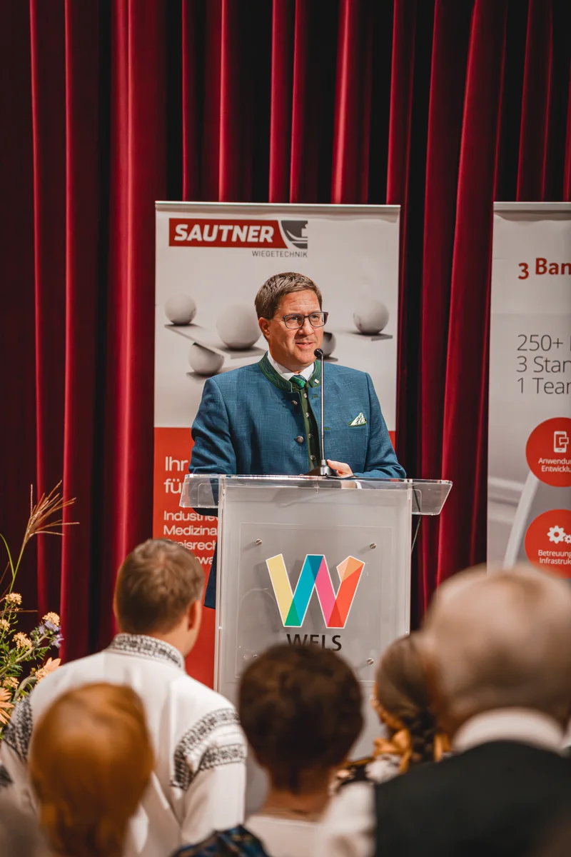 RawmanPictures - Sebastian Schiefermayr | Volkstanzfest | Redner bei Veranstaltung, vor rotem Vorhang. Business-Event-Fotografie.
