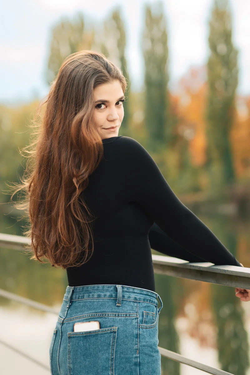 RawmanPictures - Sebastian Schiefermayr | Portraitshooting Vanessa S. | Eine Frau auf einer Brücke im Herbst, lächelt in die Kamera.