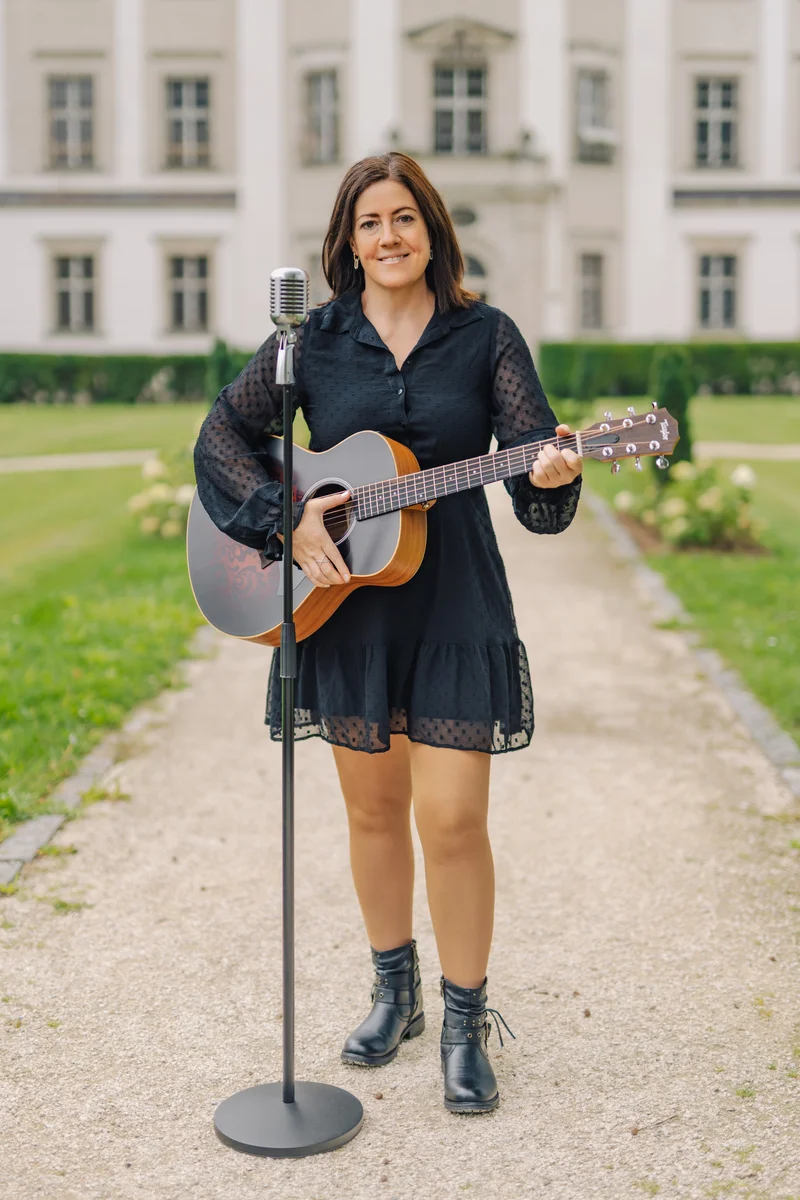 RawmanPictures - Sebastian Schiefermayr | Portraitshooting Tamara R. | Singer with guitar performing outdoors in front of elegant building. Portrait photography session.