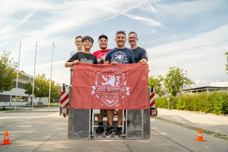 RawmanPictures - Sebastian Schiefermayr | Sommereisdisco | Eine Gruppe glücklicher Menschen bei einem sonnigen Outdoor-Event mit einem Banner.