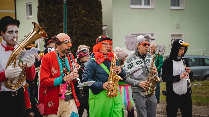 RawmanPictures - Sebastian Schiefermayr | Faschingsumzug Weißkirchen | Musiker in bunten Kostümen spielen Saxophon auf einem Straßenfest.