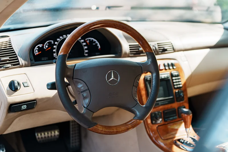 RawmanPictures - Sebastian Schiefermayr | Motortag Feldkirchen | Luxusautoinnenraum mit edlem Holzlenkrad und eleganter Armaturentafel, fotografiert in natürlichem Licht.