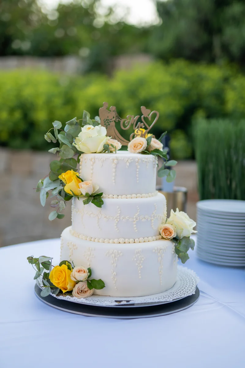 RawmanPictures - Sebastian Schiefermayr | Hochzeit Traude & Gerhard | Elegante Hochzeitstorte im Freien, verziert mit Blumen und personalisiertem Topper.