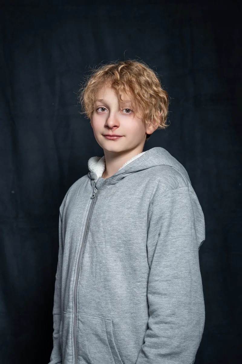RawmanPictures - Sebastian Schiefermayr | Portrait-Shooting Ozon | Porträtfotografie Kind, grauer Hoodie, dunkler Hintergrund, Studioaufnahme.