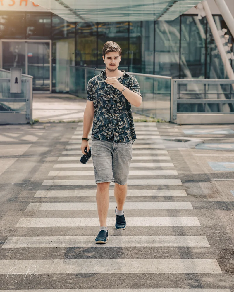 RawmanPictures - Sebastian Schiefermayr | Personal Shooting | Fotograf auf Zebrastreifen mit Kamera, urbaner Stil, Sommermode, moderner Außenbereich.