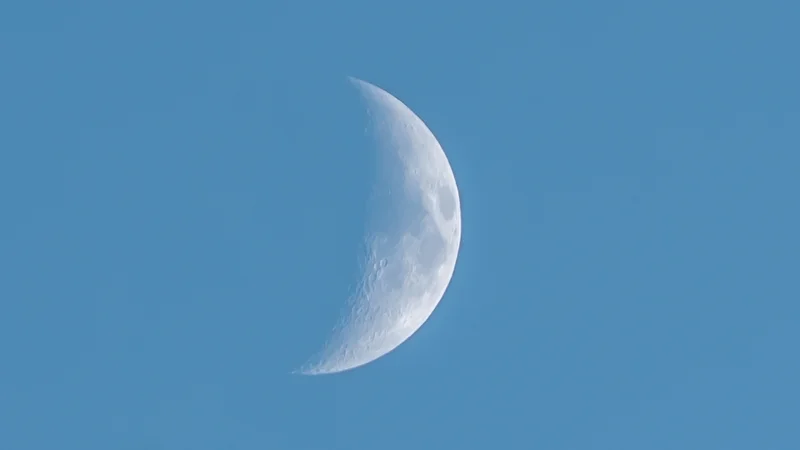 RawmanPictures - Sebastian Schiefermayr | Chioggia 2022 | Mondfotografie, Halbmond bei Tageslicht, Astronomie, klarer Himmel, Detailaufnahme des Mondes.