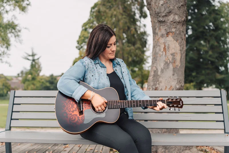 RawmanPictures - Sebastian Schiefermayr | Portraitshooting Tamara R. | Musikerin auf Parkbank mit Gitarre, Naturfotografie, kreative Outdoor Fotografie.