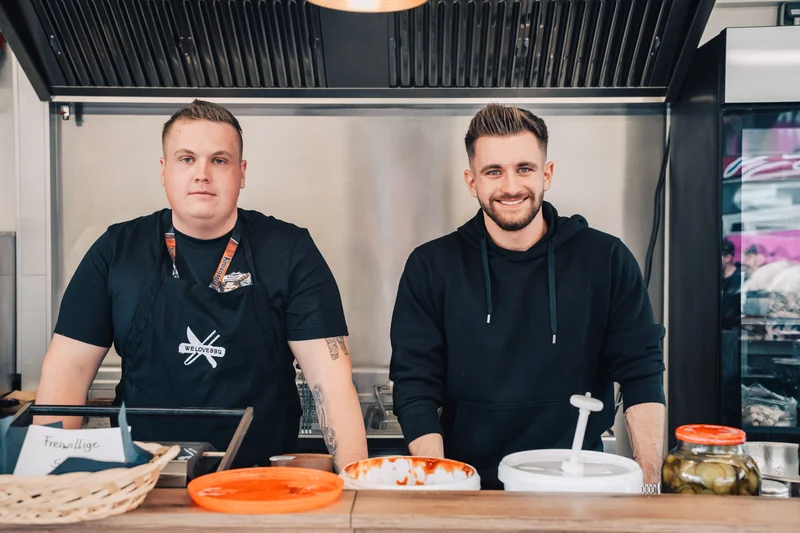 RawmanPictures - Sebastian Schiefermayr | Maskenausstellung | Street Food Stand mit freundlichen Köchen: Authentische Essensfotografie im urbanen Ambiente.