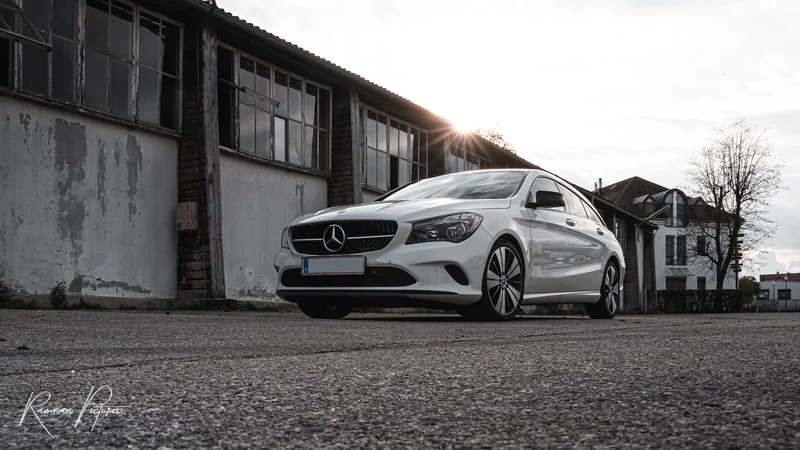 RawmanPictures - Sebastian Schiefermayr | Shooting Julian S. | Weißer Mercedes CLA vor urbanem Industriegebäude, künstlerische Autofotografie.