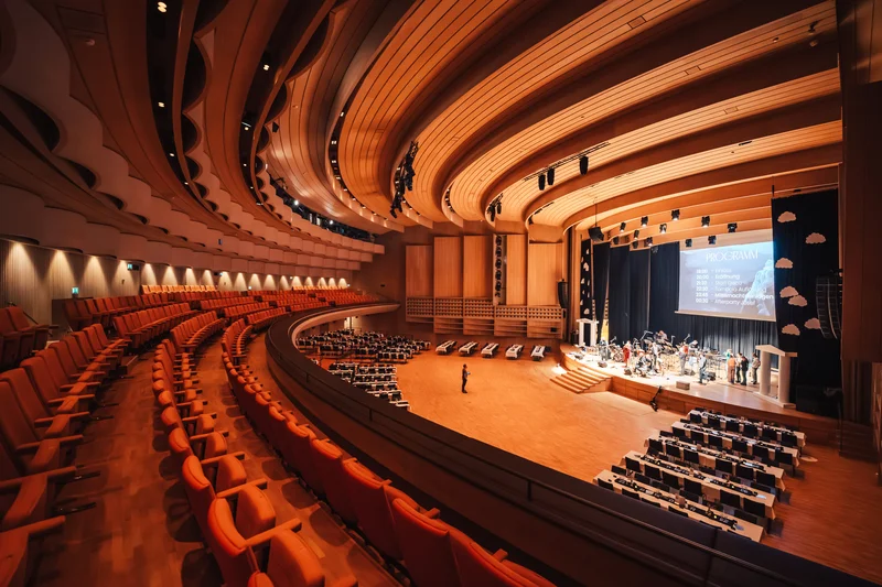 RawmanPictures - Sebastian Schiefermayr | Maturaball HTL1 | Moderne Konzerthalle mit geschwungenem Holzdesign und Bühne für Events und Musikaufführungen.