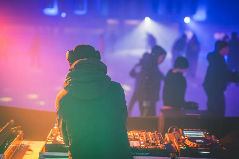 RawmanPictures - Sebastian Schiefermayr | Eisdisco Marchtrenk | DJ performt auf bunter Eislaufbahn, stimmungsvolle Event-Fotografie mit Lichteffekten.
