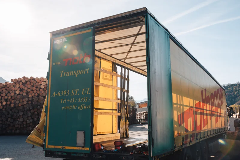 RawmanPictures - Sebastian Schiefermayr | Sägewerk Löberbauer | Offener Lkw-Anhänger für Transportaufträge im sonnigen Industriehintergrund. Logistikmanagement.