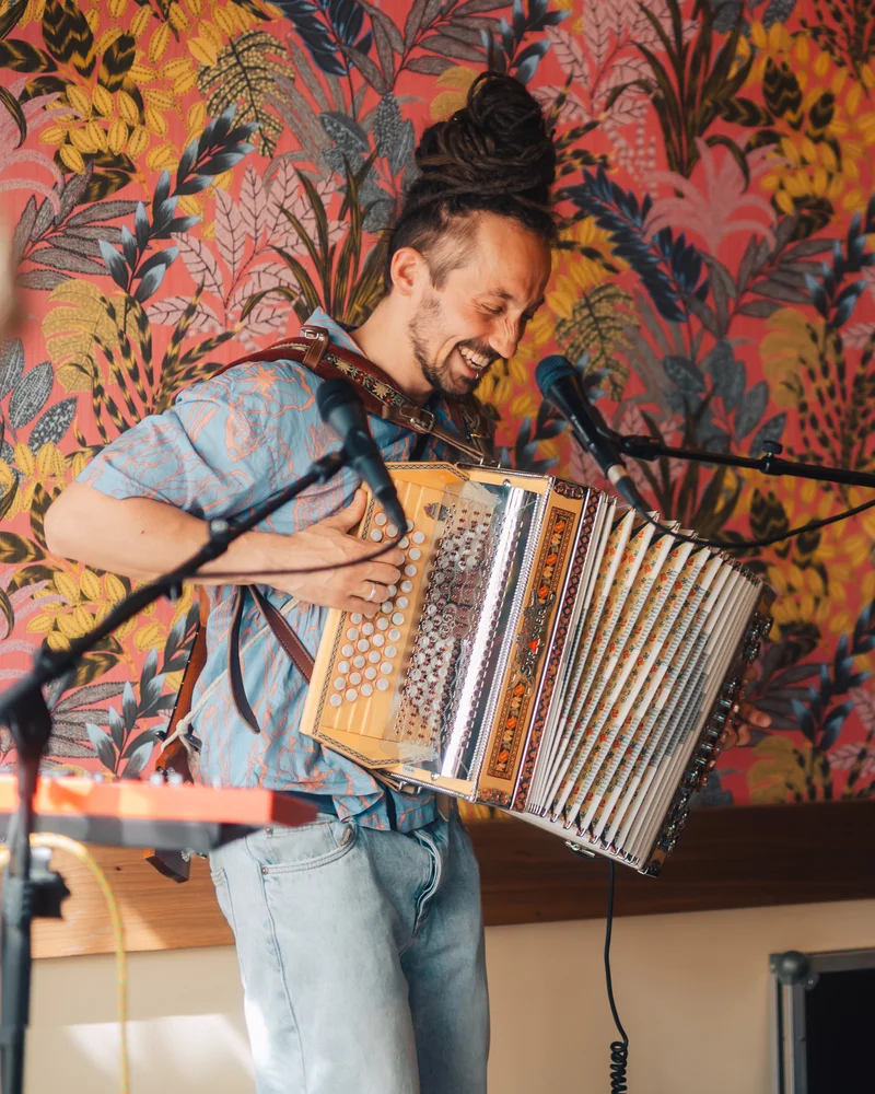 RawmanPictures - Sebastian Schiefermayr | Charity Brunch | Musiker mit Akkordeon, Farbe, Freude, Musik, Eventfotografie, Innenaufnahme, lebendige Kulisse.