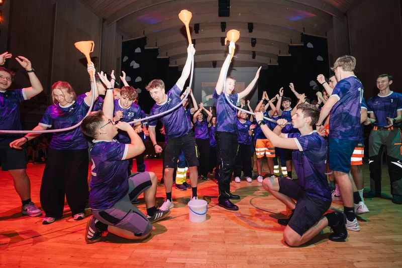 RawmanPictures - Sebastian Schiefermayr | Maturaball HTL1 | Jugendliche feiern in einer Halle ein Team-Event, leuchtende Atmosphäre, dynamische Gruppenaktivität.