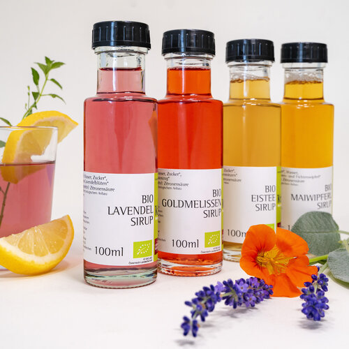 RawmanPictures - Sebastian Schiefermayr | Kräuter­manufaktur Sallmannsberg | Bio-Sirup-Flaschen mit Blüten und Glas, ideal für Getränke und kreative Rezeptfotografie.