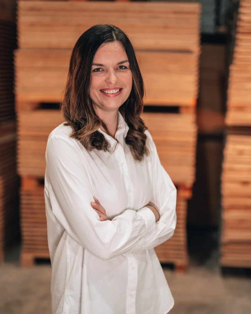 RawmanPictures - Sebastian Schiefermayr | Firmenshooting EasyBox GmbH | Frau in weißem Hemd vor gestapeltem Holz, professionelle Porträtfotografie für Business.