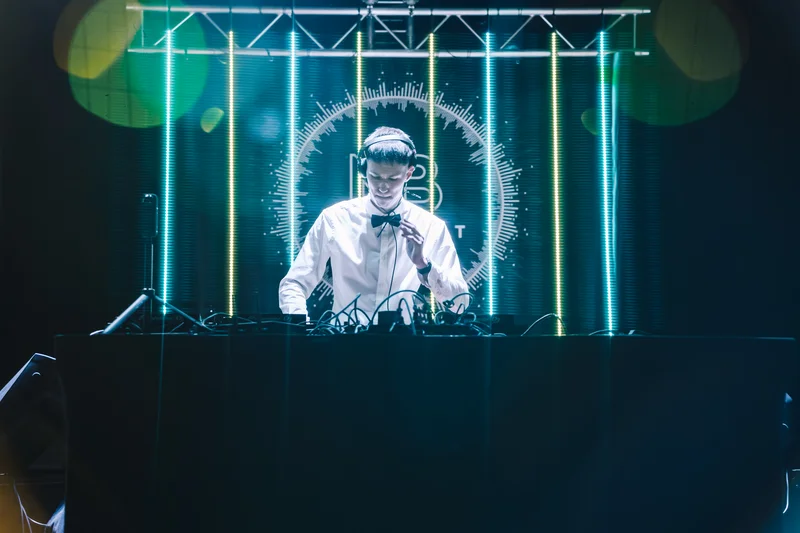 RawmanPictures - Sebastian Schiefermayr | Maturaball HTL1 | DJ bei einem dynamischen Live-Set mit farbenfroher Lichtshow und modernem Bühnenhintergrund.