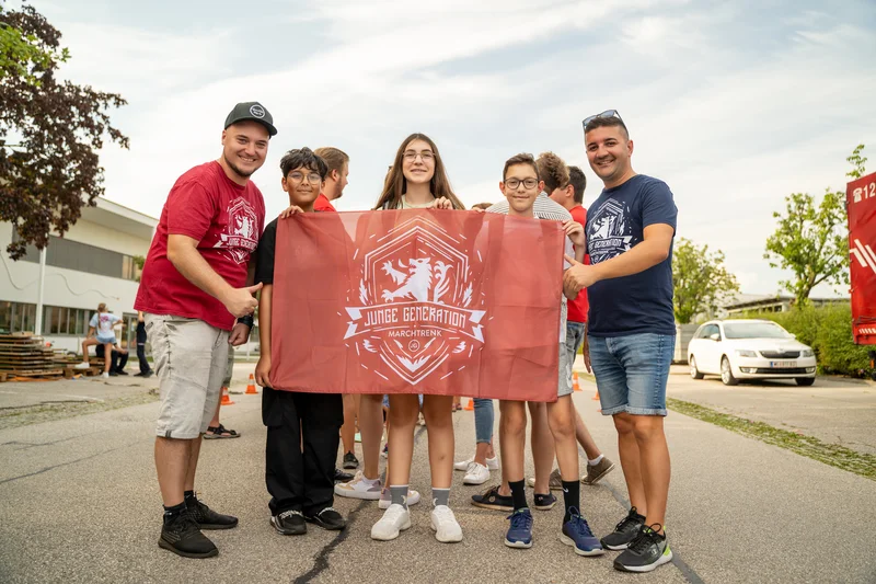 RawmanPictures - Sebastian Schiefermayr | Sommereisdisco | Gruppe hält Banner beim Outdoor-Event: Gemeinschaft, Freude, Sommer, Teamwork, Zusammenhalt.