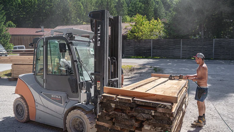 RawmanPictures - Sebastian Schiefermayr | Sägewerk Löberbauer | Holzverarbeitung im Sägewerk: Gabelstapler transportiert Holz bei Tageslicht.