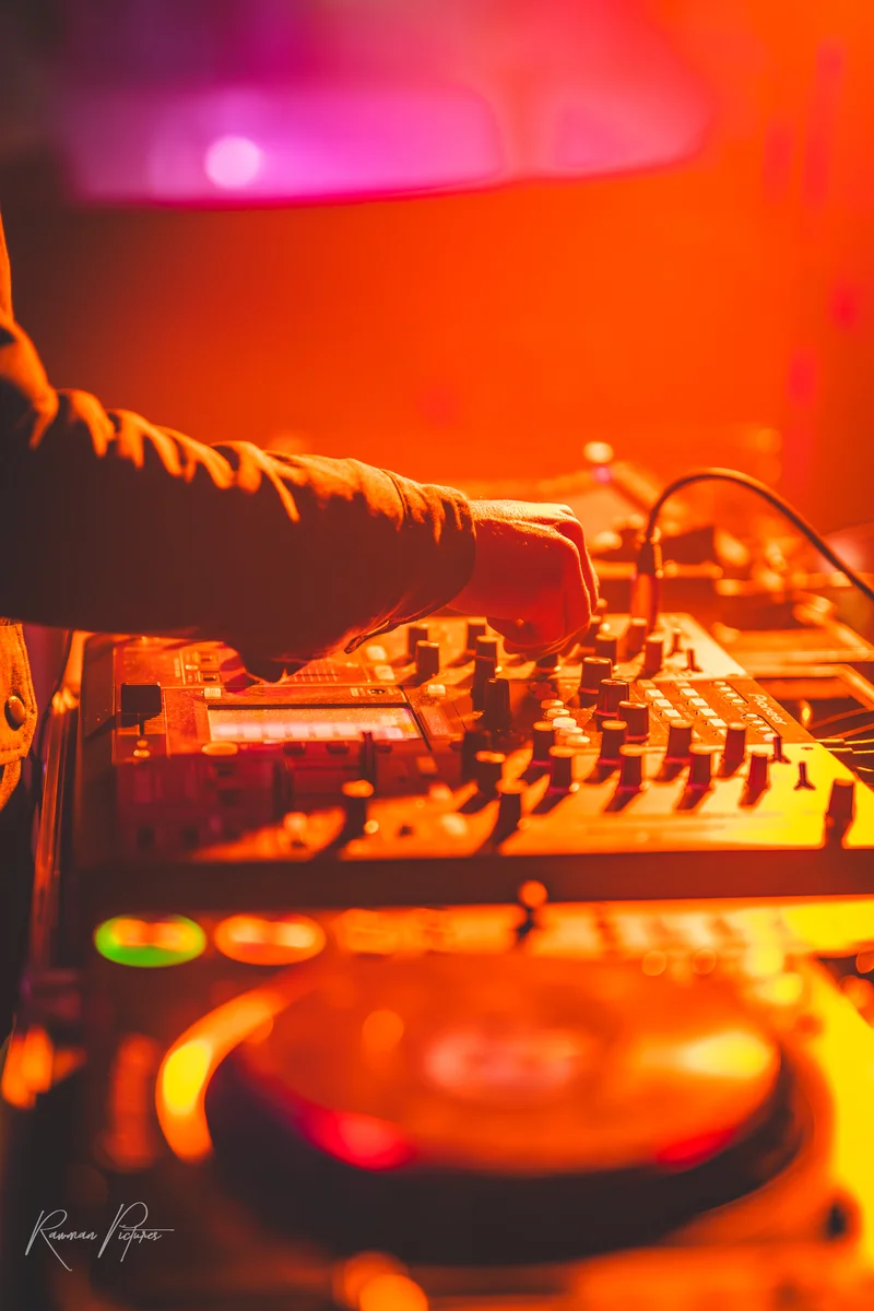 RawmanPictures - Sebastian Schiefermayr | Eisdisco Marchtrenk | DJ bei der Arbeit an einem Mixer auf der Bühne, stimmungsvolle Beleuchtung, Eventfotografie.