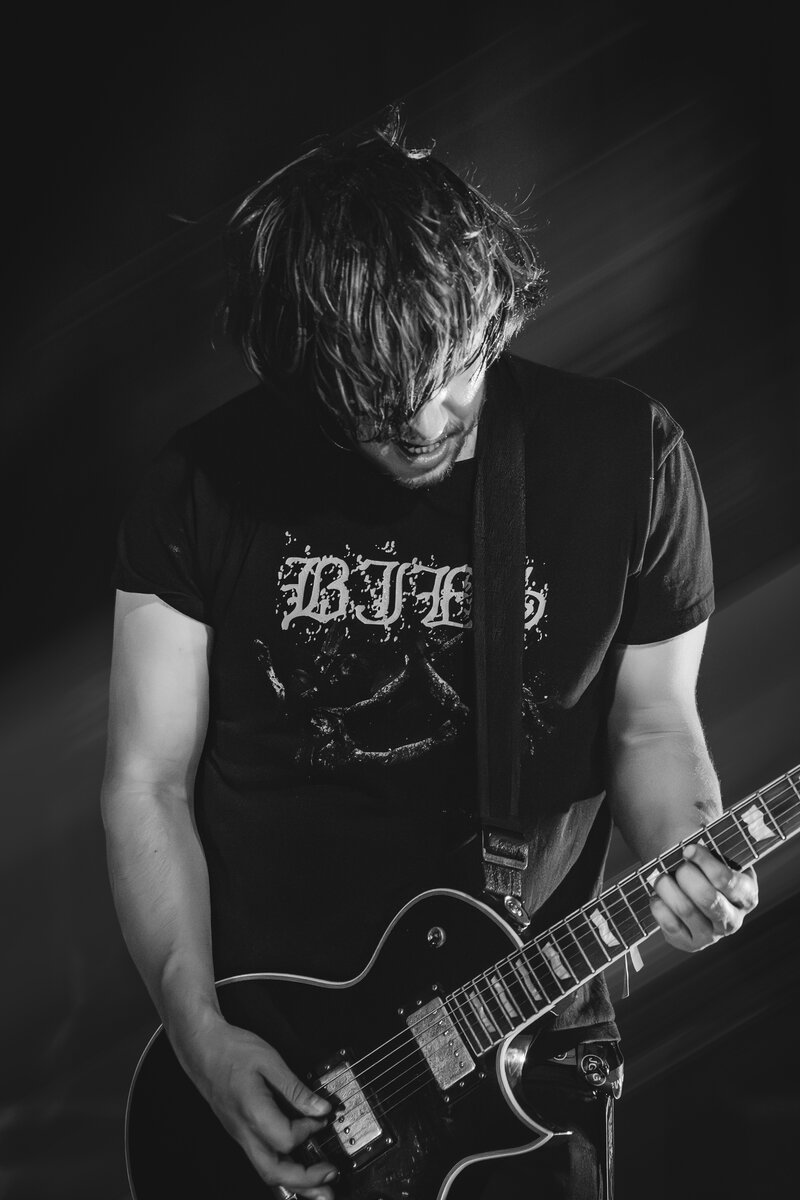 Schwarzweiß-Fotografie eines Gitarristen in Aktion auf der Bühne. Konzertfotografie Highlight.