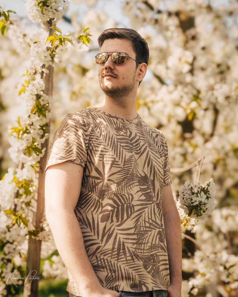 RawmanPictures - Sebastian Schiefermayr | Kirschblüten­wanderung  | Portraitfotografie im Frühling, Mann mit Sonnenbrille vor blühenden Bäumen.