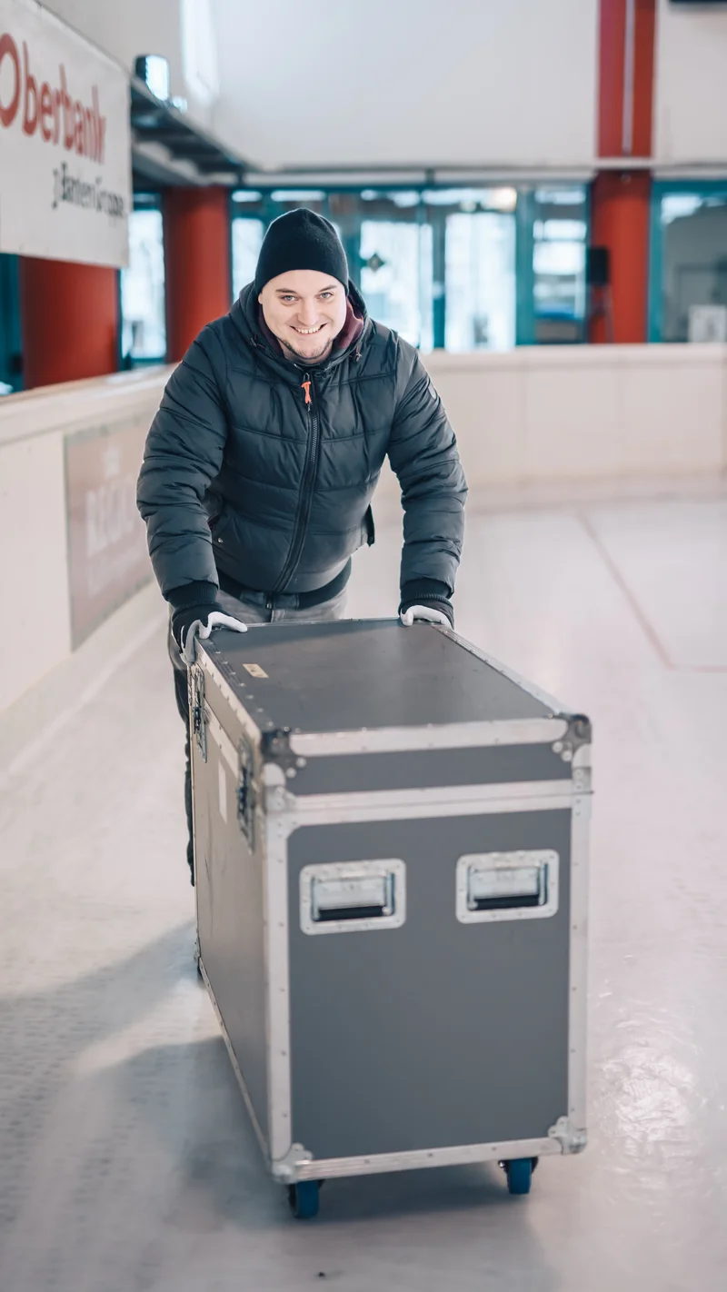 RawmanPictures - Sebastian Schiefermayr | Eisdisco Marchtrenk | Ein Mann transportiert eine Box auf einer Eisbahn. Winter, Logistik, kaltes Wetter, Porträt.