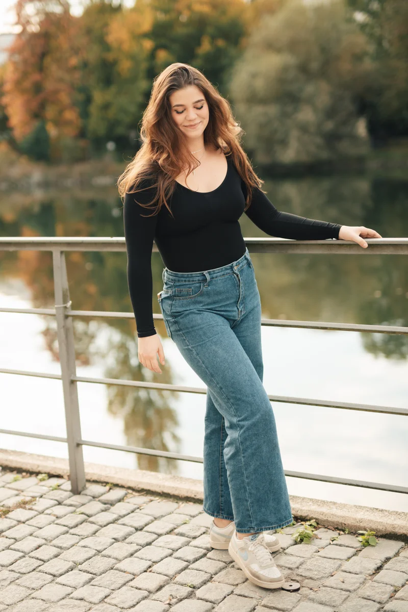 RawmanPictures - Sebastian Schiefermayr | Portraitshooting Vanessa S. | Person am Flussufer in Freizeitkleidung, herbstliche Stimmung, natürliche Fotografie.